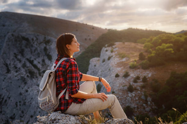 istock woman hiker enjoy the view at sunset mountain peak cliff 1276641069