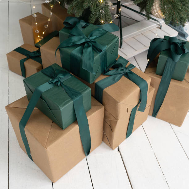 istock New Years presents lie under the Tree. Gifts in brown boxes and green packaging. Boxes decorated with ribbons and bows. Close up shot 1276642307