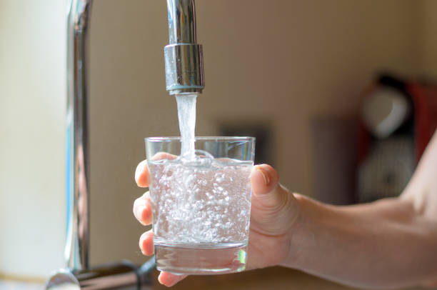 蛇口からコップ一杯の水を満たす女性 - faucet glass water running water ストックフォトと画像