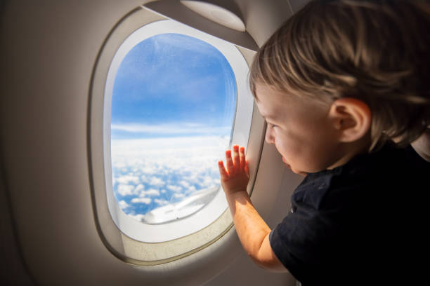 istock cute toddler points his finger at the sky through the window. first flight concept, traveling with children. 1276642923