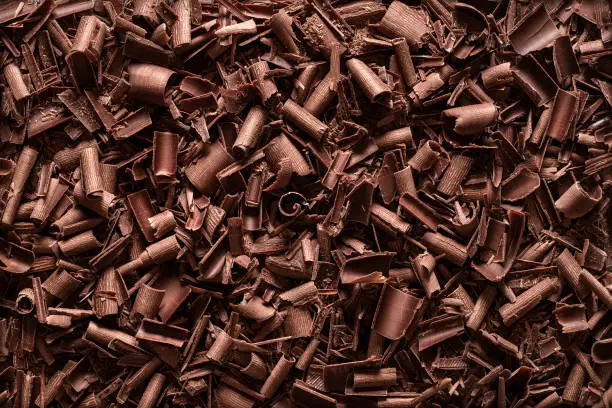 Chopped chocolate background. Flat lay of milk chocolate shavings. Close-up of baking chocolate texture.