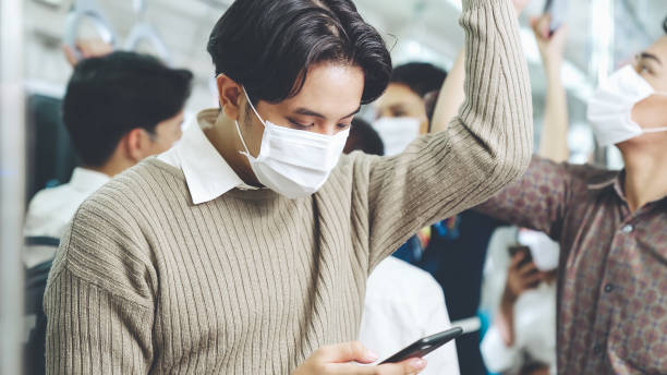 istock Traveler wearing face mask while using mobile phone on public train 1276647824