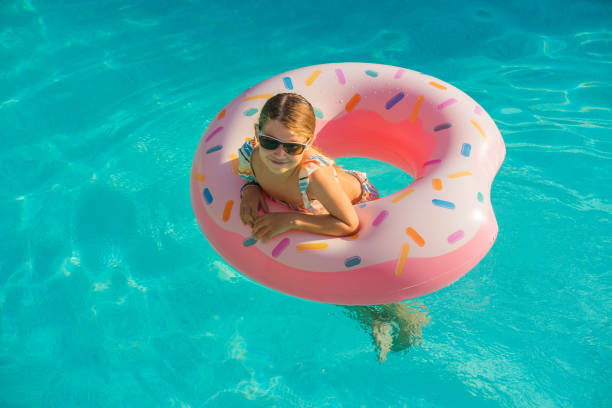 istock cute young girl playing in a swimming pool with her inflatable donuts 1276647943