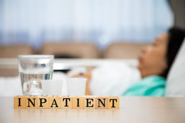 Female patient sleeping in hospital patient room with Inpatient wording block on table Female patient sleeping in hospital patient room with Inpatient wording block on table inpatient stock pictures, royalty-free photos & images