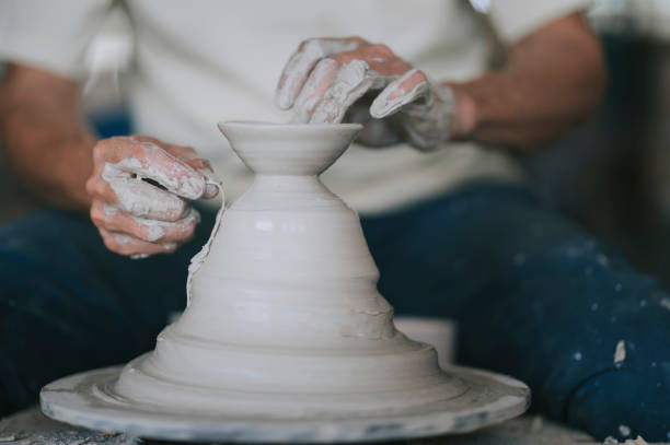 asian chinese active senior man Potter working at his workshop with spinning pottery wheel