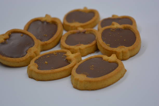 istock Fresh delicious crunchy shortbread cookies with nutty, chocolate filling inside. Apple-shaped cookies with brown filling located on a white matte background. 1276651230