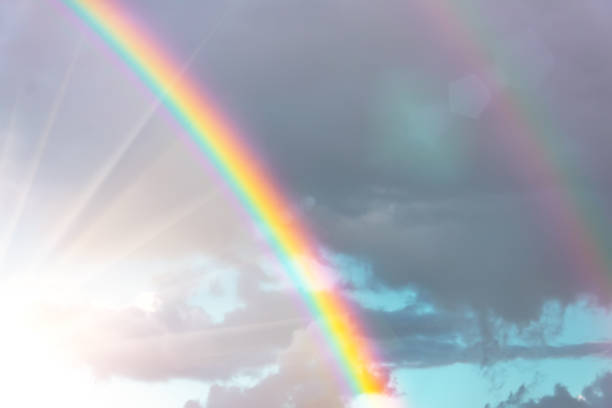 arco iris real con resplandor de sol brillante y rayos de sol rayos en el cielo entre las nubes después de la lluvia. - arco iris fotos fotografías e imágenes de stock