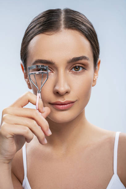 istock Young elegant woman with eyelash curler isolated on white background 1276652090
