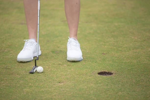 feche acima da golfista chinesa asiática batendo na bola para um buraco de golfe no campo de golfe. - golf women female concentration - fotografias e filmes do acervo