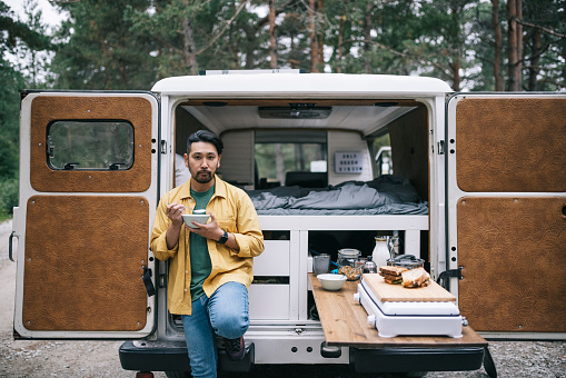 Man eating breakfast next to his camper van