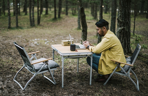 Japanese man workig with laptop in nature.