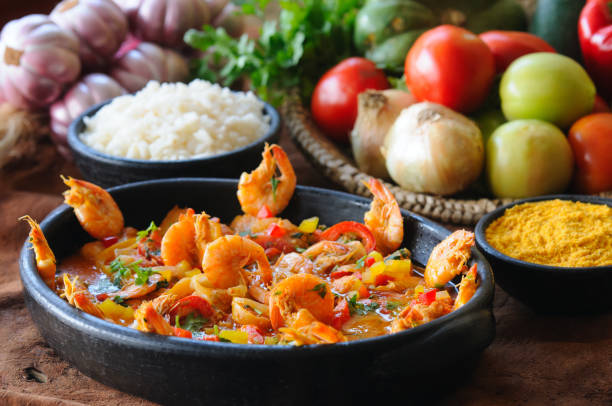 Shrimp stew in a clay bowl, accompanied with rice and manioc flour. Traditional dish of Brazilian cuisine. stock photo