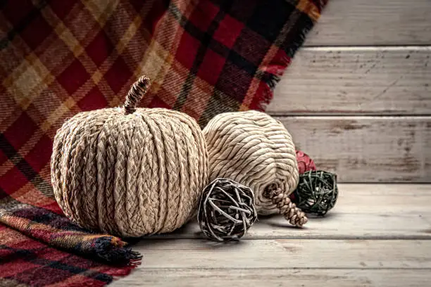 This is a close up photo of white tweed pumpkins on a plaid felt and wood textured background. There is space for copy. This image would work well for autumn, fall, Thanksgiving and a holiday Halloween season in the fall.