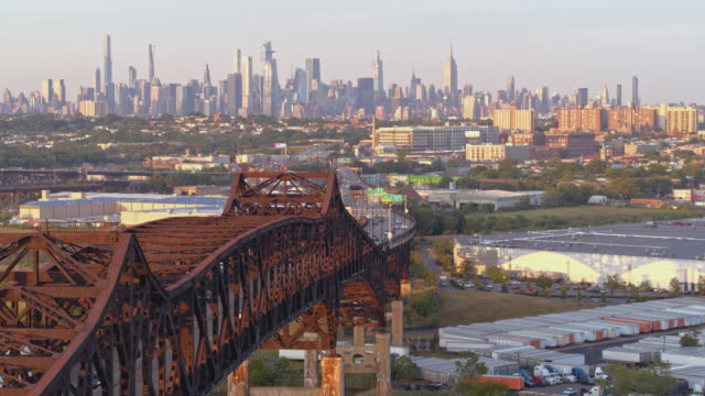 Remote aerial view of Manhattan, New York City, over General Pulaski Bridge - Pulaski Skyway, New Jersey, at sunset. Aerial drone video with the forward camera motion.