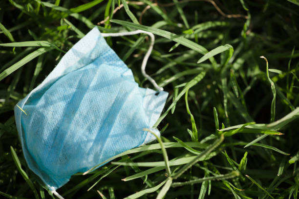 istock Waste during COVID-19. Discarded to single-use coronavirus face masks. Environmental pollution, on fresh grass 1276660011