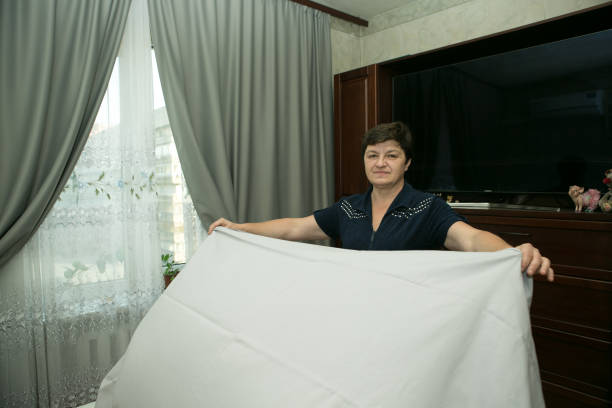 homework. a middle-aged woman covers fresh bedding. - n64 imagens e fotografias de stock