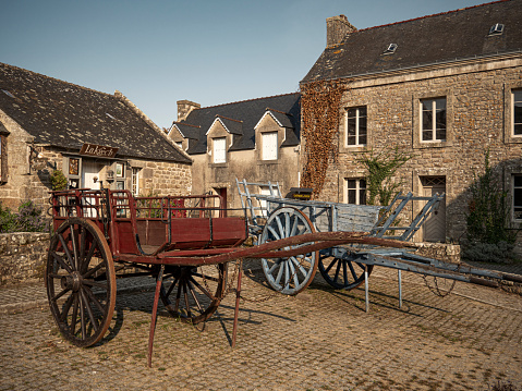 Locronan, France : September 11, 2020 An empty old horse cart an the entrance of  Locronan Brittany France It is considered as one of the most beautiful villages in this country. It is  an old town of the XVI century.