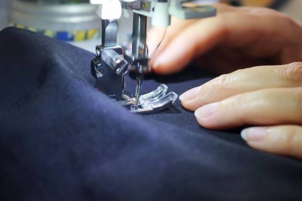 istock Sewing concept. Female hands working at a modern sewing machine with some fabrics and textiles 1276666315