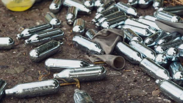 istock Discarded Nitrous Oxide canisters and grey ballon 1276666445
