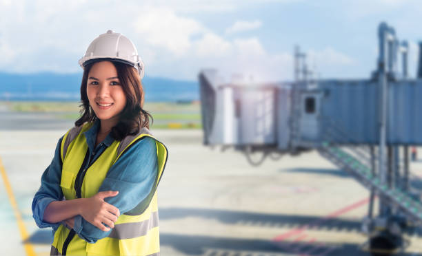 Aviation Confidence Female asian Engineer with safety equipment with Airport in the background. stock photo
