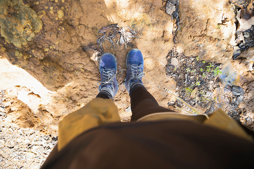 View from above of female climber boots climbing the mountain on dirt and rock terrain