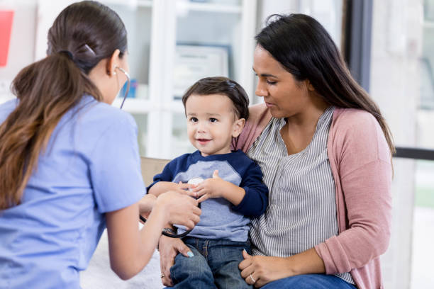 istock Sitting in mom's lap, boy looks at unrecognizable nurse 1276680016