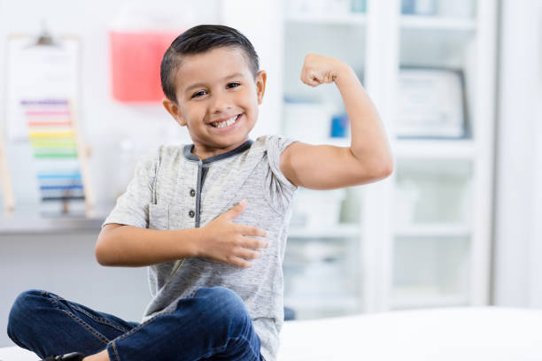 istock Elementary age boy looks at camera and flexes arm muscles 1276680040