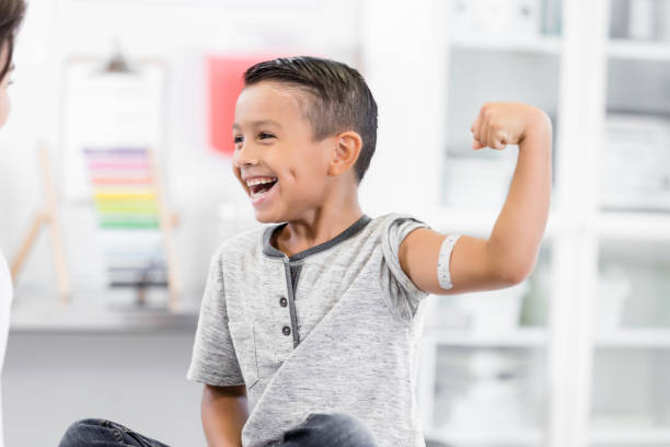 istock Boy laughs with unrecognizable doctor while flexing arm muscle 1276680041