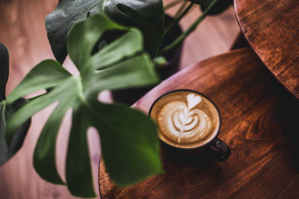 istock Hot coffee latte on wooden table with monstera plant 1276681264