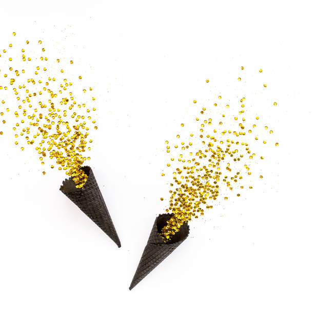 istock Black waffle cones with golden confetti tinsel isolated on white background. Flat lay, top view minimal festive concept 1276684781