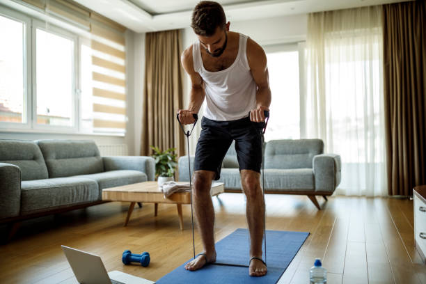 Young athletic man training with stretching band at home Young athletic man training with stretching band at home strap photos stock pictures, royalty-free photos & images