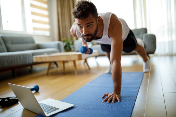 młody człowiek za pomocą laptopa i ćwiczenia w domu - exercising men push ups muscular build zdjęcia i obrazy z banku zdjęć