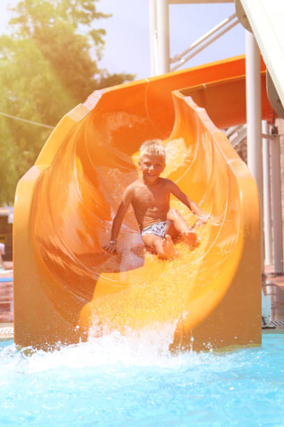 istock happy boy quickly going on the orange water slide 1276686411