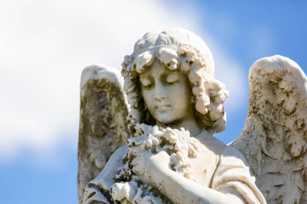 istock Angel, old statue of angle with flowers, blue sky background with copy space 1276687090