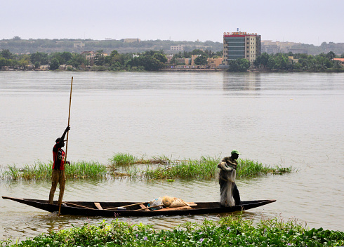 Bamako, Mali: Niger River fishermen on a canoe, near the corniche, with Badalabougou quarter in the background