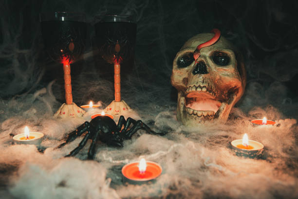 istock Halloween decorations. A human skull with a snake, next to two wine glasses decorated with spiders and skulls, standing on a web 1276687435