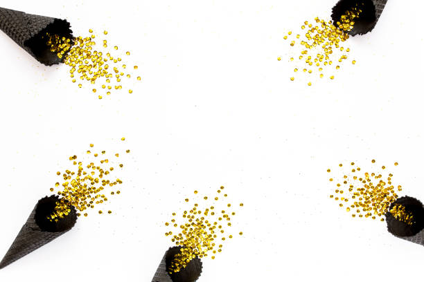 istock Black waffle cones with golden confetti tinsel isolated on white background. Flat lay, top view minimal festive concept 1276688271