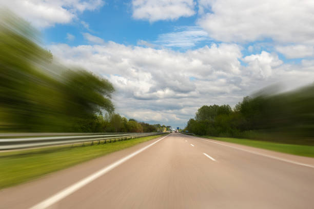 emtpy suburaban route de voiture d’autoroute avec le mouvement brouillé vitesse rapide conduisant contre le ciel bleu sur le fond. paysage d’autoroute de véhicule de perspective - car street horizon over land sky photos et images de collection