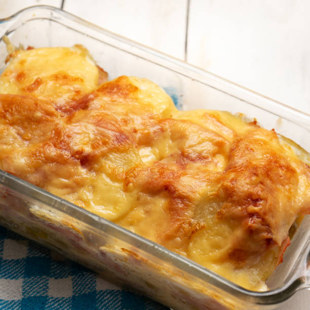 istock Scalloped potatoes with ham and cheese on white background 1276693396