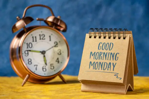 Good Morning Monday - cheerful handwriting a spiral notebook with a alarm clock, new week in the office concept