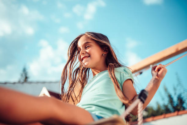 портрет счастливой маленькой девочки, сидящей на качелях и улыбающейся - child swing swinging playing стоковые фото и изображения