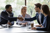 Smiling diverse employees handshake at briefing in office