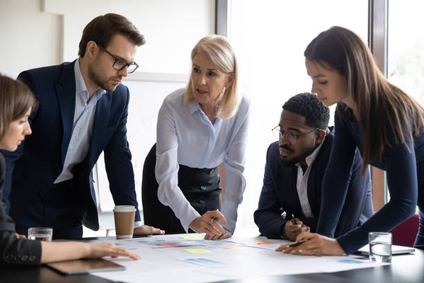 istock Focused diverse businesspeople discuss paperwork at meeting 1276706777