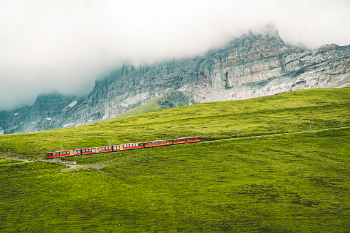 Famous railway from Wengen and Lauterbrunnen valley to Jungfraujoch. Red modern mountain train driving trough Swiss Alps.