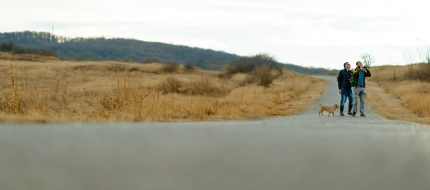 istock Friends with a dog hiking down the road 1276707204