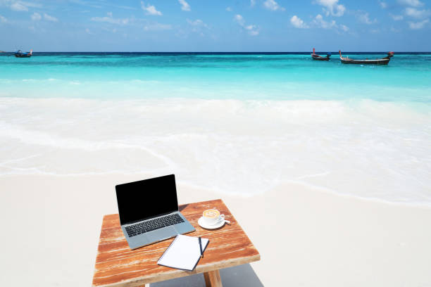 istock Mobile work office on the sunny beach with blank laptop screen 1276712250