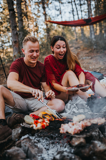 couple preparing a food in nature, campfire
