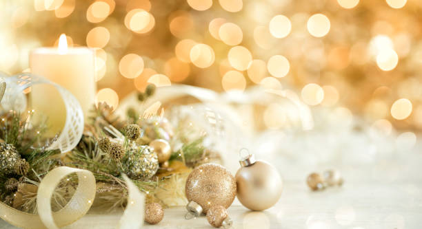 Christmas Gold Ornaments and Candle Christmas Elegant Gold Candle and Ornaments against a Golden Lights Christmas Tree Background candlelight photos stock pictures, royalty-free photos & images