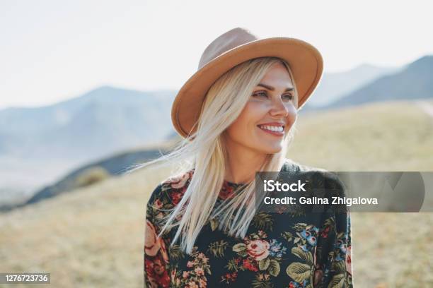 Beautiful Smiling Blone Young Woman Traveler In Dress And Felt Hat On Road Trip To The Mountains Altai Stock Photo - Download Image Now