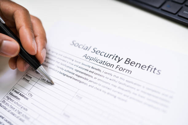 istock Person's Hand Filling Social Security Benefits Application Form 1276731820